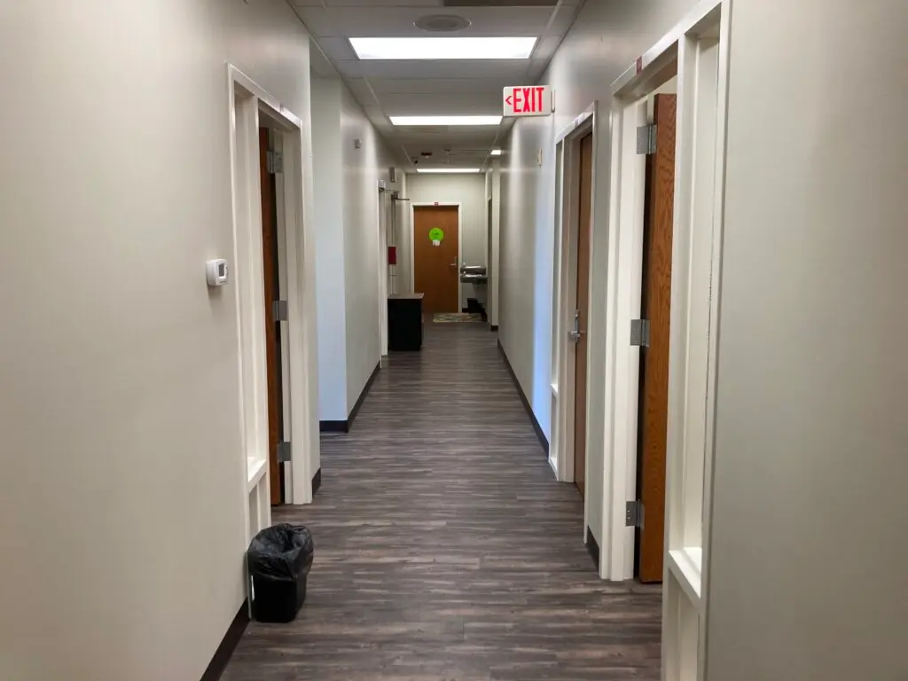a-long-hallway-with-a-trash-can-on-the-floor
