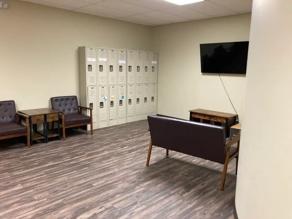 a room with a television, chairs, and lockers.