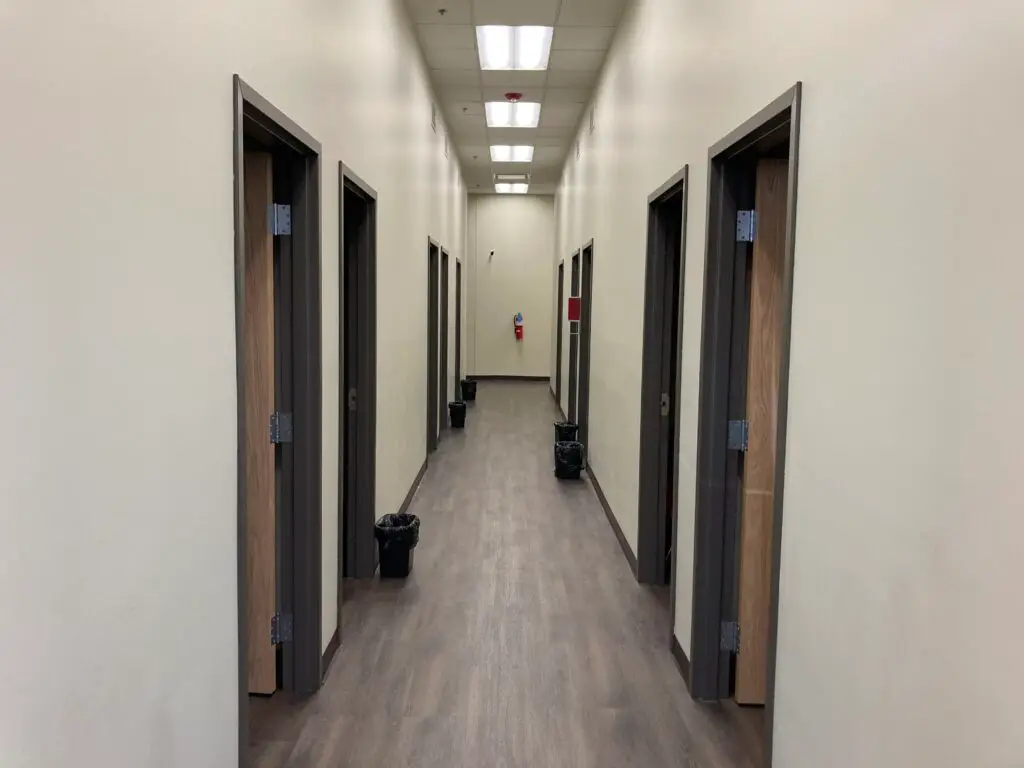 a-long-hallway-with-several-doors-leading-to-another room