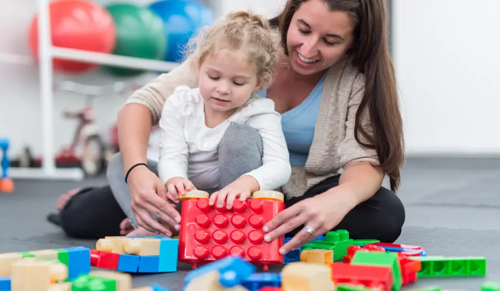 woman playing with toy blocks with a young girl