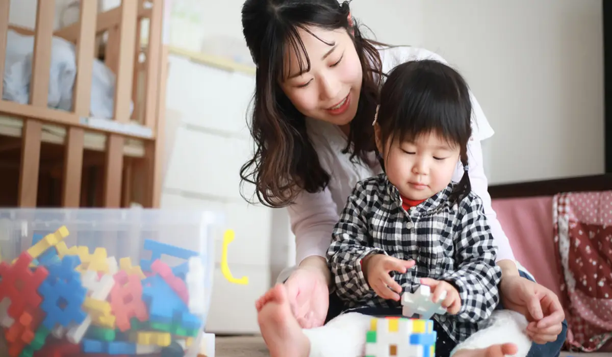 A mother and her child playing with toy blocks.